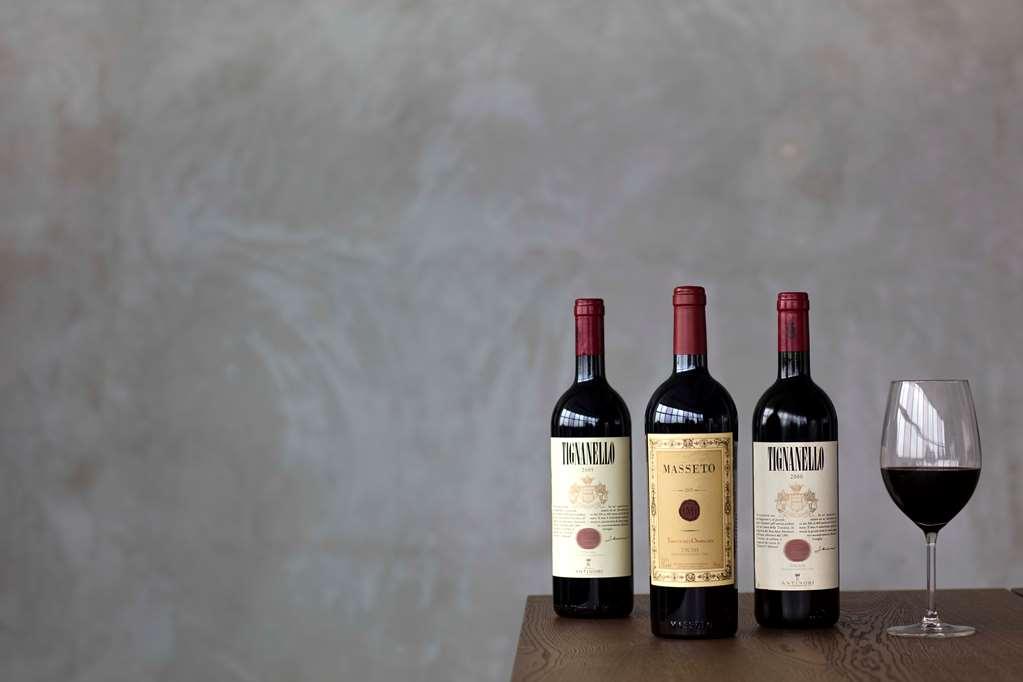 Carlton Hotel Singapore Ristorante foto The photo features three bottles of red wine placed on a wooden table against a textured, muted background. The bottles have distinct labels, and positioned beside them is a glass of red wine, filled and reflecting light. The overall composition sugg