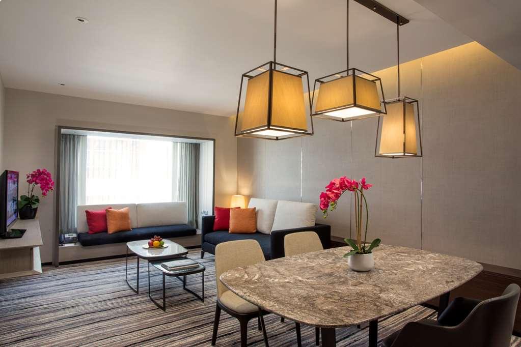 Carlton Hotel Singapore Amenities foto The photo shows a modern living space with a cozy atmosphere. There are three pendant lights hanging from the ceiling, providing soft illumination. On one side, a comfortable seating area features a sofa adorned with colorful cushions, while a large 
