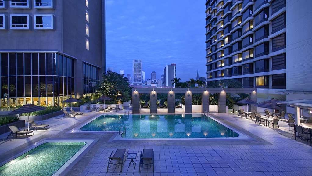 Carlton Hotel Singapore Servizi foto The image shows a pool area at dusk, surrounded by buildings. There are two swimming pools; one is larger and rectangular, while a smaller, square pool is nearby. Lounge chairs are arranged around the pools, and there are several palm trees and decor