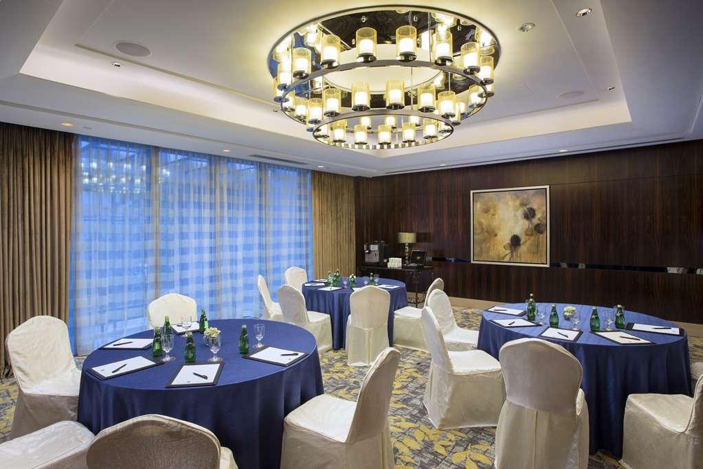 Carlton Hotel Singapore Servizi foto The photo shows an elegant conference or event room. It features several round tables covered with dark blue tablecloths, each set with white chairs and decorative items like small glass bottles. Above, there is a large, modern chandelier providing a