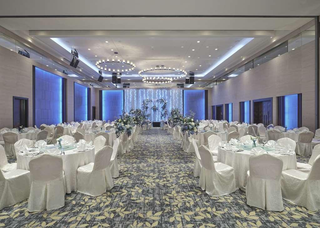 Carlton Hotel Singapore Servizi foto The photo shows a beautifully arranged banquet hall. The space features round tables covered with white tablecloths and adorned with centerpieces, possibly floral arrangements. The chairs are also draped in white fabric. The hall has a spacious layou