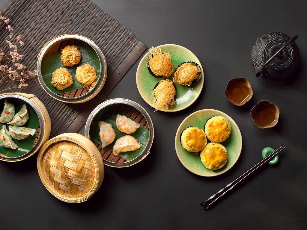 Carlton Hotel Singapore Ristorante foto The photo showcases an elegant arrangement of various types of dim sum on green plates. There are several bamboo steamers, some filled with dumplings and others with baked items like pastries. The dishes include dumplings that appear to be steamed, p