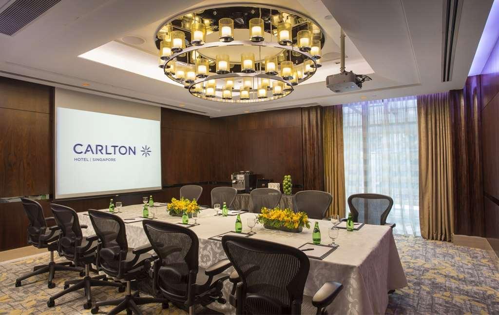 Carlton Hotel Singapore Servizi foto The image shows a professional meeting room in a hotel. The room features a large table set with light-colored tablecloths and several chairs around it. At the center of the table, there are decorative arrangements with yellow flowers. A large screen