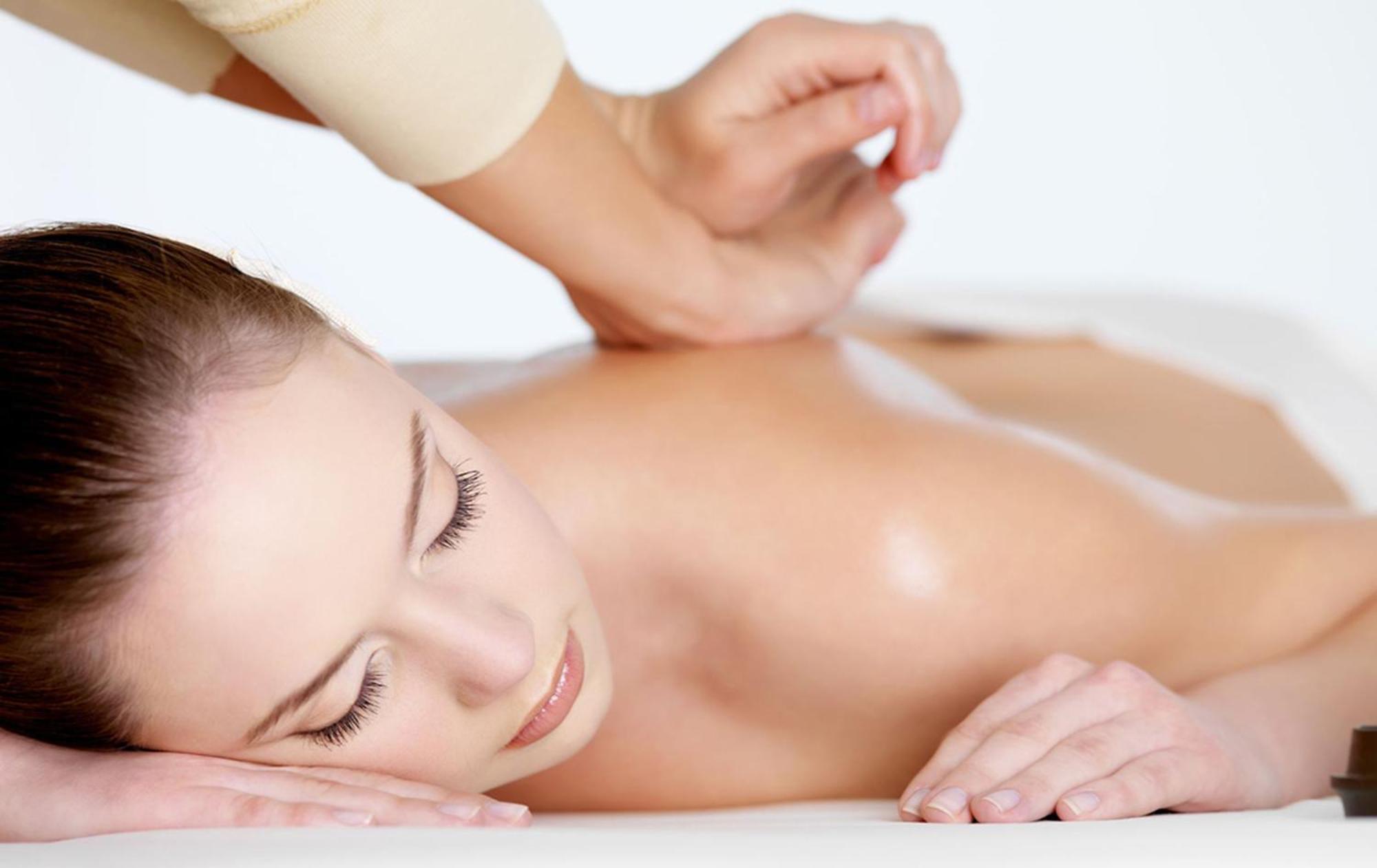 Carlton Hotel Singapore Esterno foto The image shows a woman lying on a massage table, appearing to receive a massage. Her head is turned to the side, and she has a calm expression. There is a hand visible in the foreground gently applying pressure on her back, indicating a soothing the