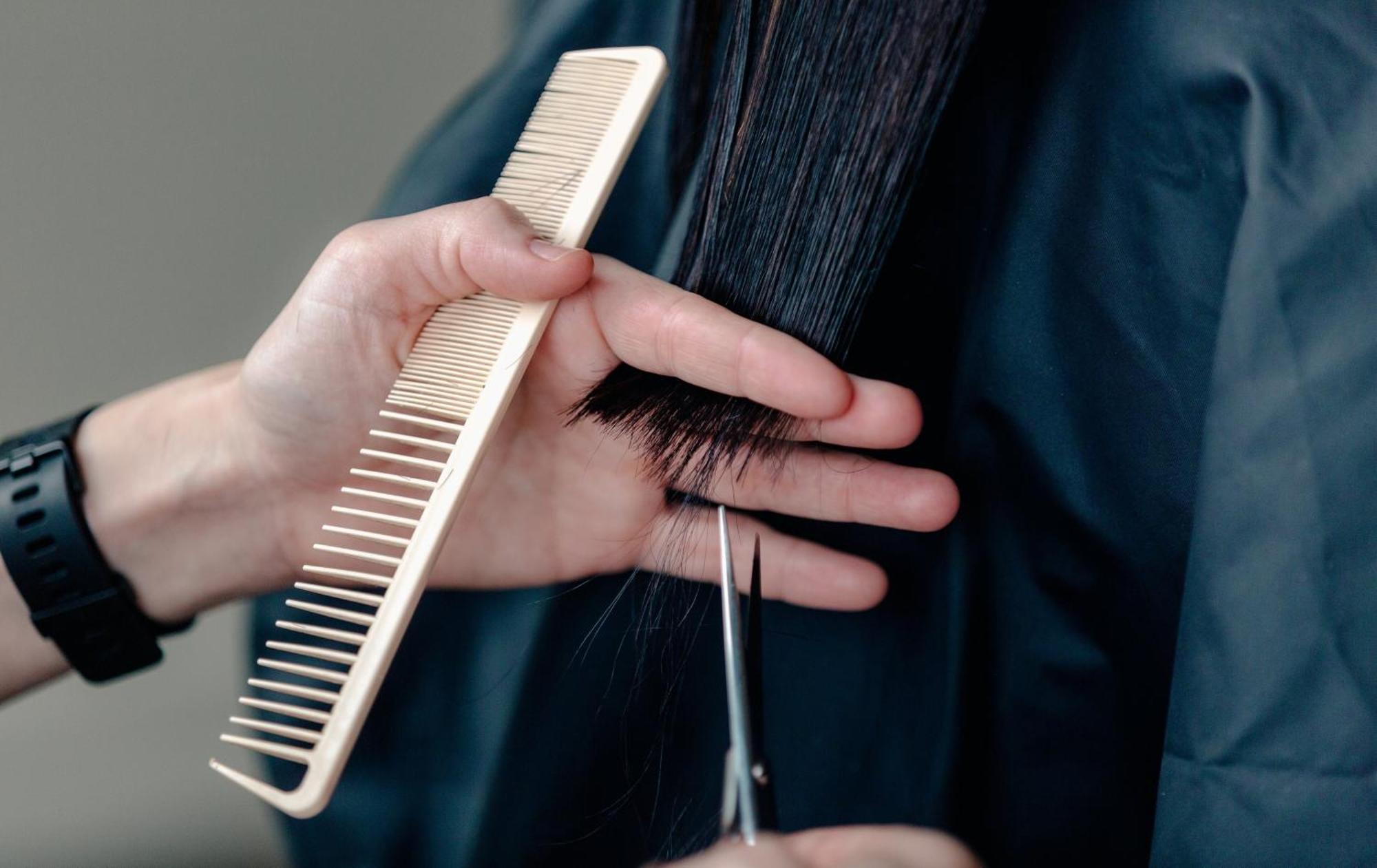 Carlton Hotel Singapore Esterno foto The photo shows a person holding a comb in one hand and scissors in the other. The comb is positioned near the ends of long, dark hair, which is being held with fingers. The scissors are poised for cutting, indicating that this is a hairstyle trimmin