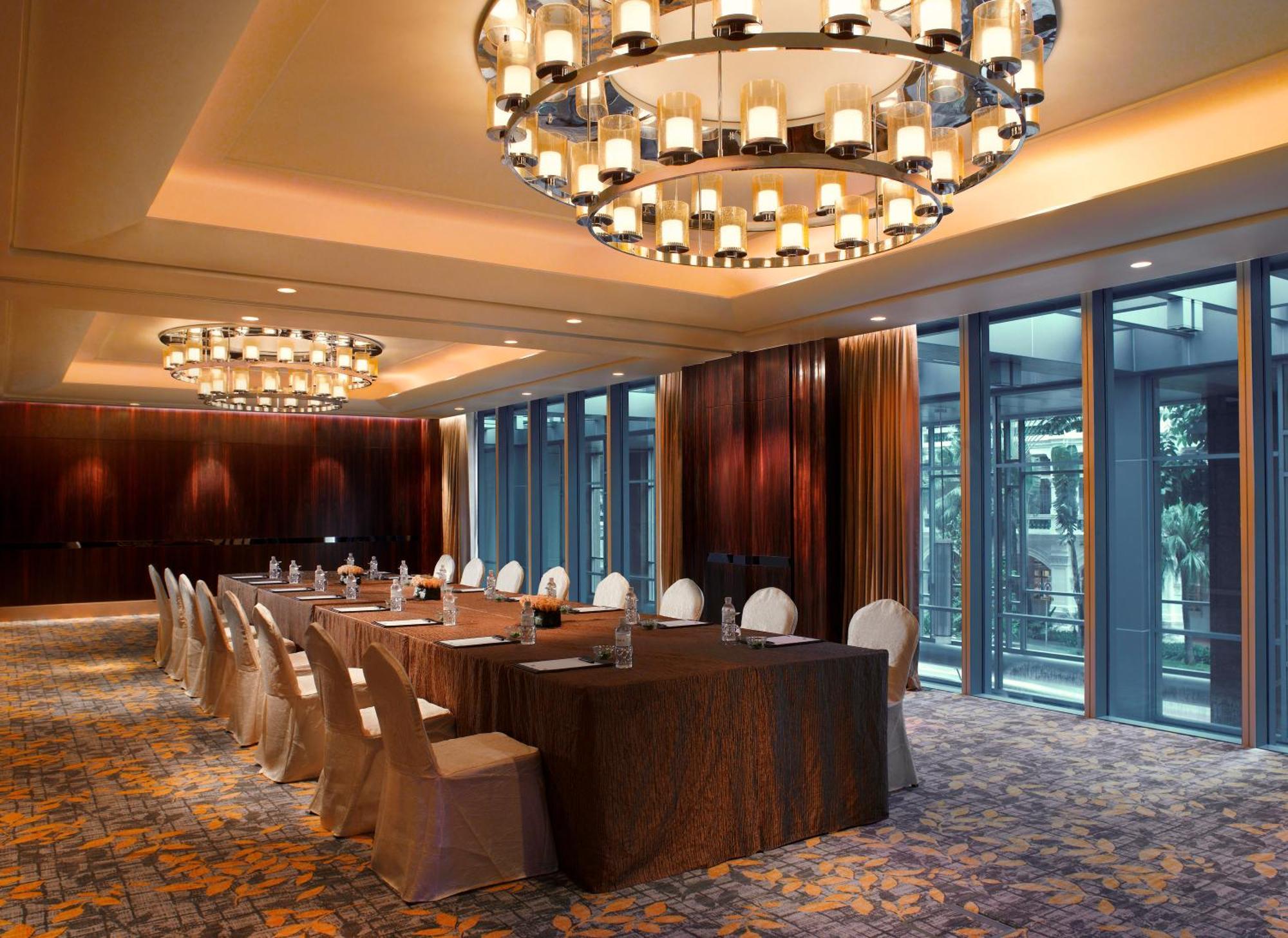 Carlton Hotel Singapore Esterno foto The photo shows a spacious, elegantly designed meeting or banquet room. It features a long rectangular table surrounded by chairs, suitable for a formal gathering. The room is softly illuminated by large decorative chandeliers hanging from the ceilin