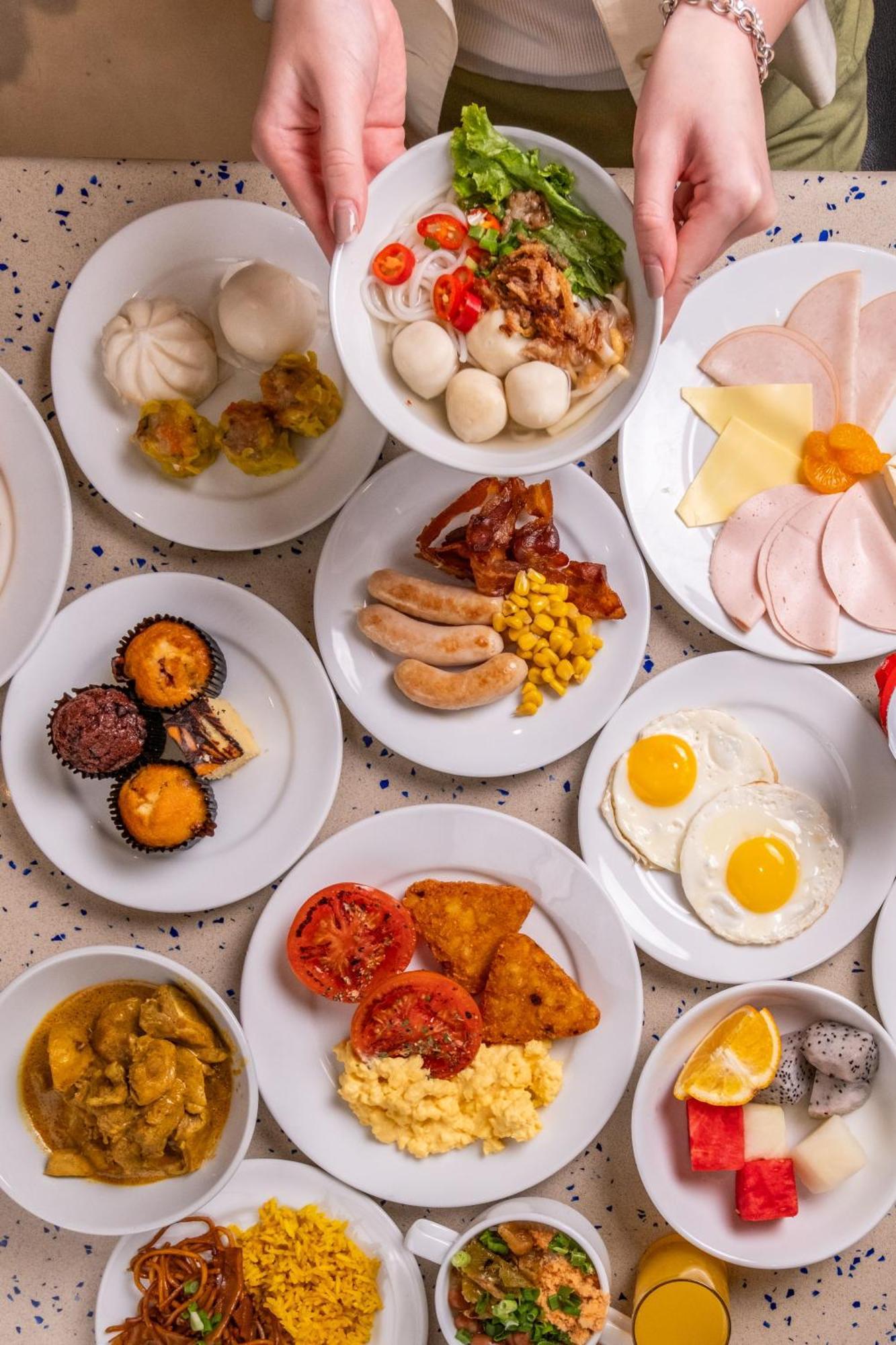 Carlton Hotel Singapore Esterno foto The photo displays a variety of food items arranged on several white plates. 

- There are dumplings, potentially steamed or filled, along with some small white balls that may be a type of dessert or snack.
- Other items include slices of ham and che