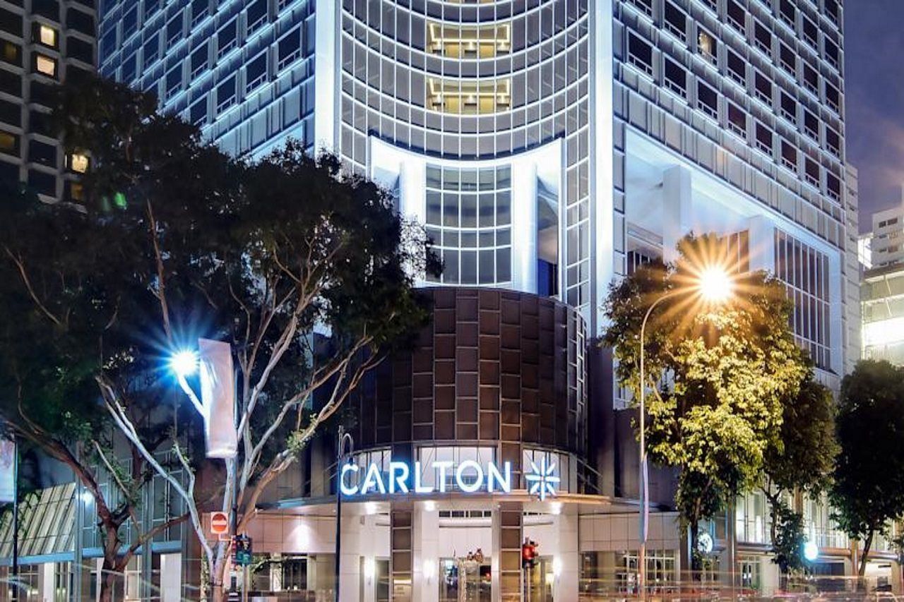 Carlton Hotel Singapore Esterno foto The photo shows the exterior of a modern building, likely a hotel or commercial establishment, prominently featuring the name "CARLTON" at the entrance. The architecture appears contemporary, with large glass windows and a sleek design. The building 