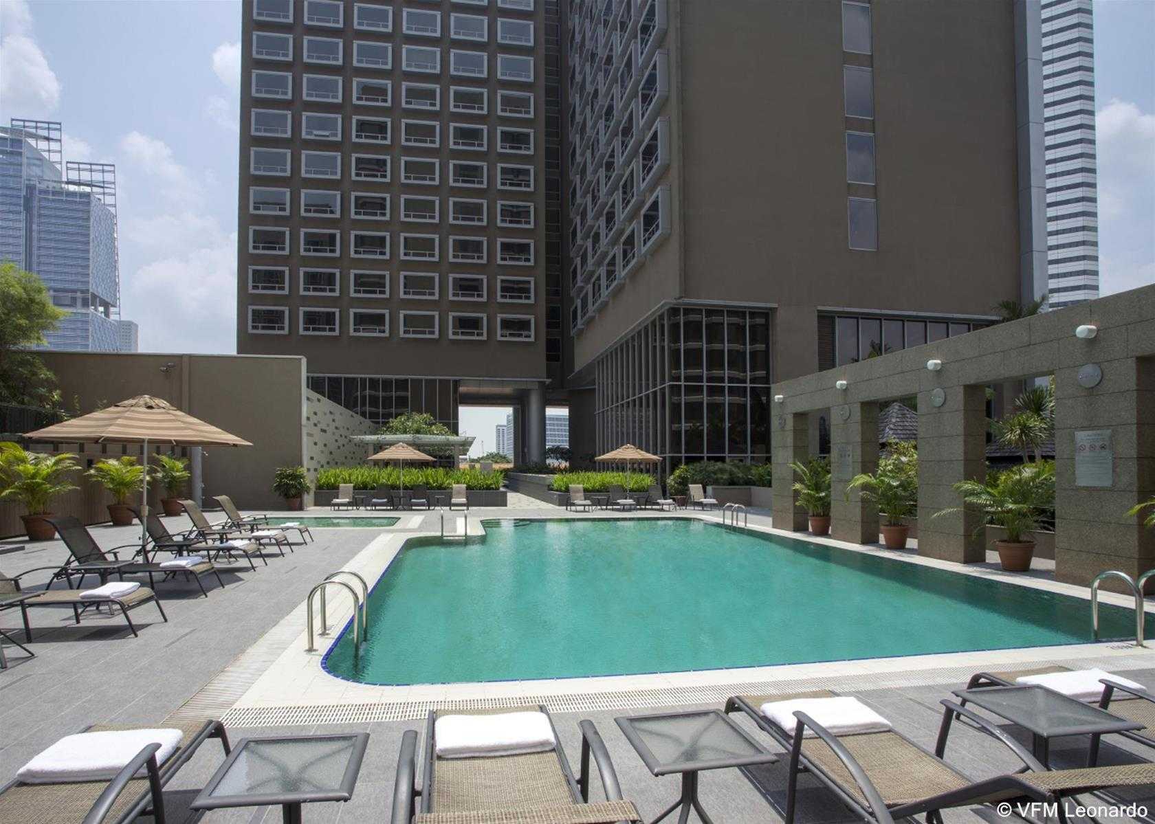 Carlton Hotel Singapore Esterno foto The photo shows a swimming pool area situated in an outdoor setting. Surrounding the pool are several lounge chairs positioned for relaxation, some of which have cushions. There are also umbrellas providing shade. In the background, there are tall bu