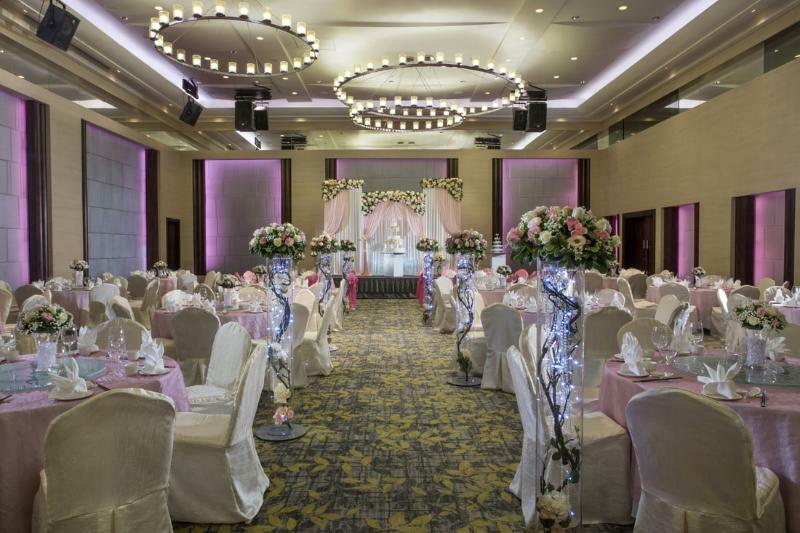 Carlton Hotel Singapore Esterno foto The photo shows a beautifully decorated banquet hall, likely set up for a wedding or a special event. The room features elegant round tables adorned with light pink tablecloths and white napkins. Each table has flower arrangements, which add a touch 