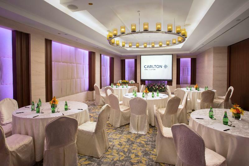 Carlton Hotel Singapore Esterno foto The image shows a well-decorated conference room or event space. There are several round tables covered with light-colored tablecloths, each accompanied by chairs that are also draped in similar fabric. On the tables, there appear to be bottles of wa