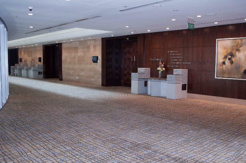 Carlton Hotel Singapore Esterno foto The photo shows a spacious and elegantly designed interior hallway. It features a patterned carpet and walls that have a mix of wood paneling and neutral colors. To one side, there are potted plants and decorative displays on low tables, giving a tou