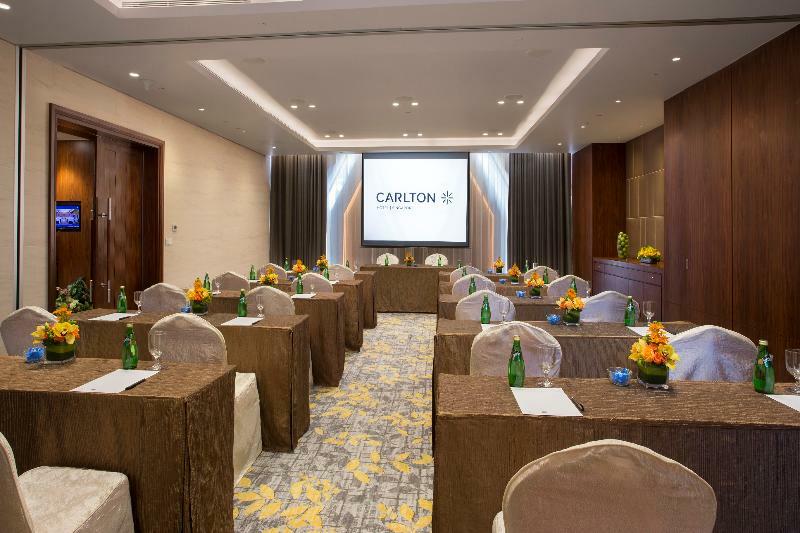 Carlton Hotel Singapore Esterno foto The photo shows a conference room setup. The room features a modern design with light-colored walls and wooden accents. In the center, there are several tables arranged in a U-shape, each covered with light-colored tablecloths. Chairs are positioned 